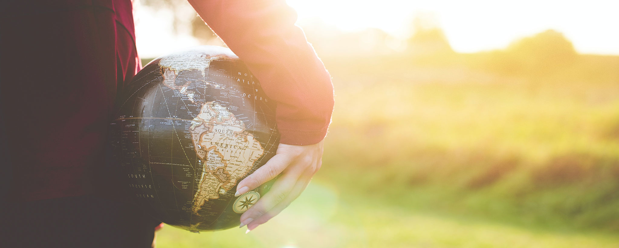 person holdling globe with out of focus field in background